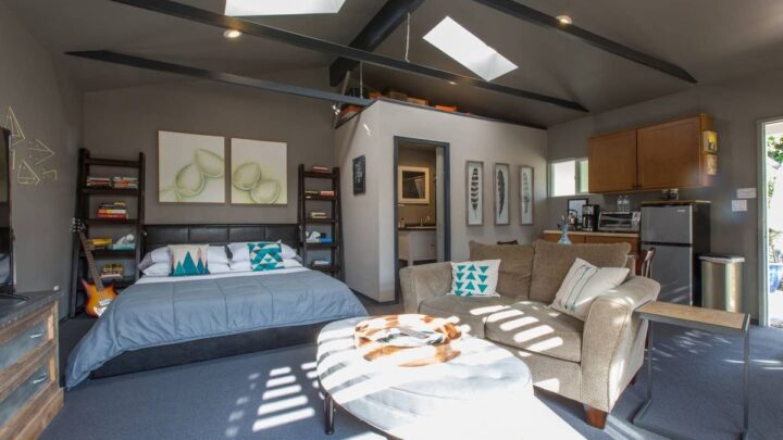 Modern studio apartment with bed, sofa and open kitchenette