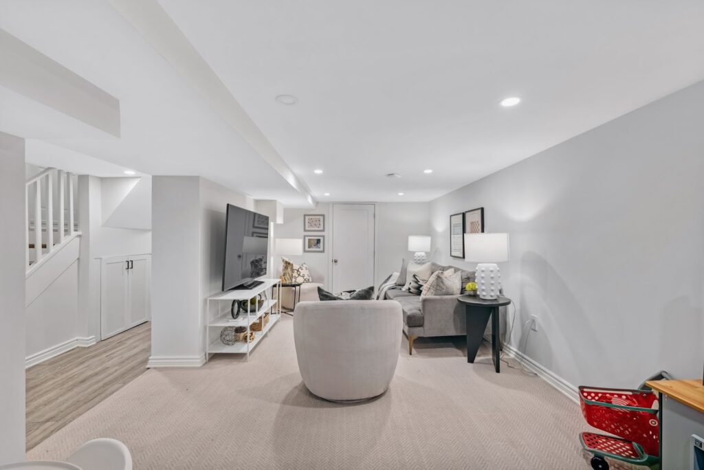 Finished basement family room with sofa, TV and bright lighting