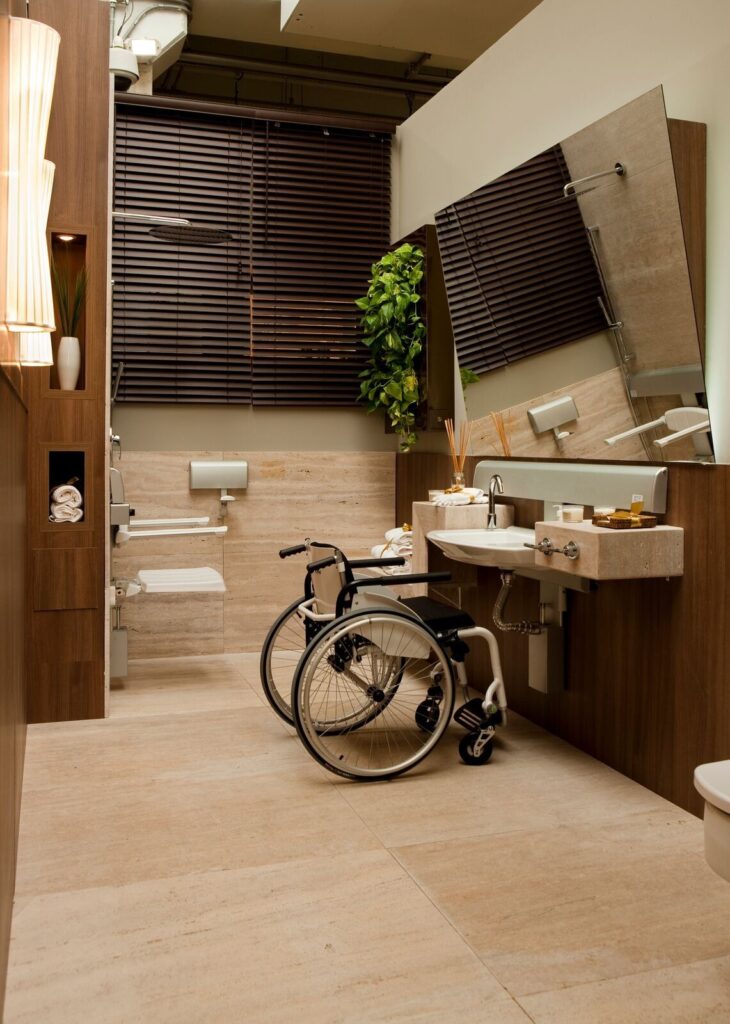Accessible bathroom with wheelchair, wall mounted sink and shower seat