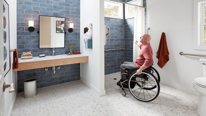 Accessible bathroom with wheelchair user reaching for roll-in shower