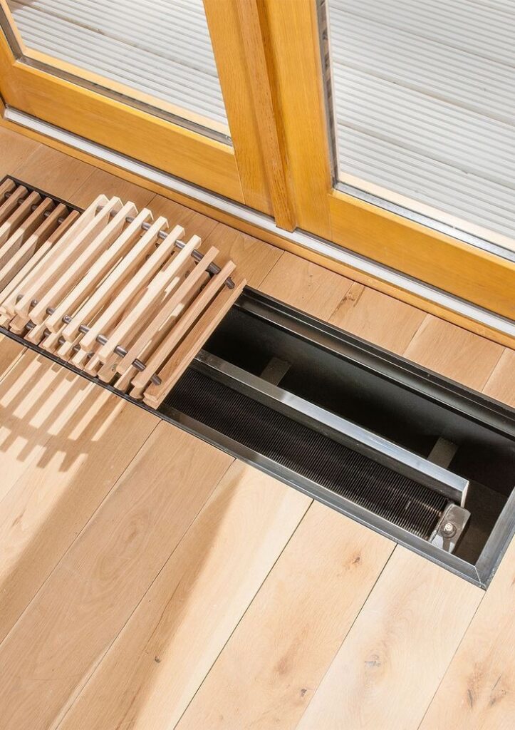 Modern floor trench heater installed under large patio doors