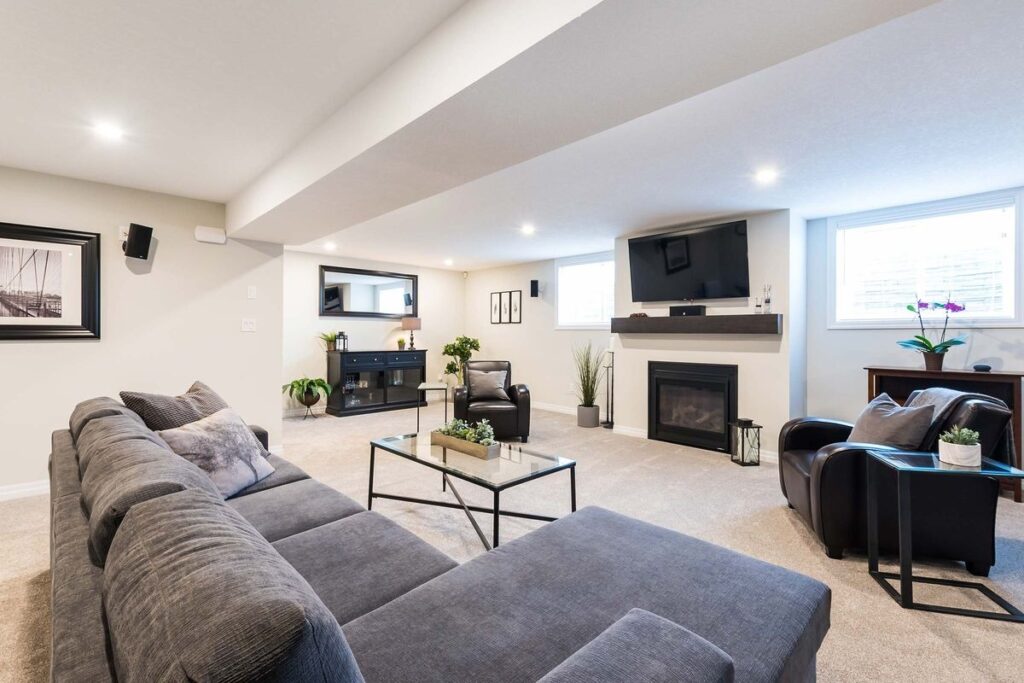 Bright finished basement with sectional sofa, fireplace, and TV